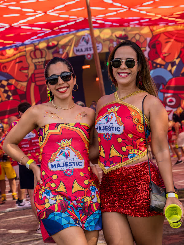 Duas amigas com o abadá vermelho do Camarote Majestic sorriem para a câmera.