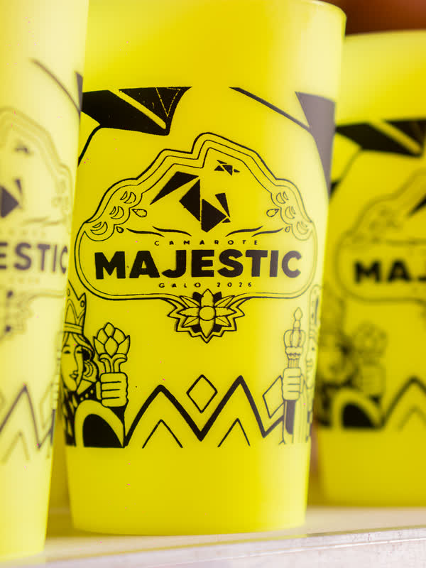 Copos amarelos com a marca Camarote Majestic empilhados no bar.
