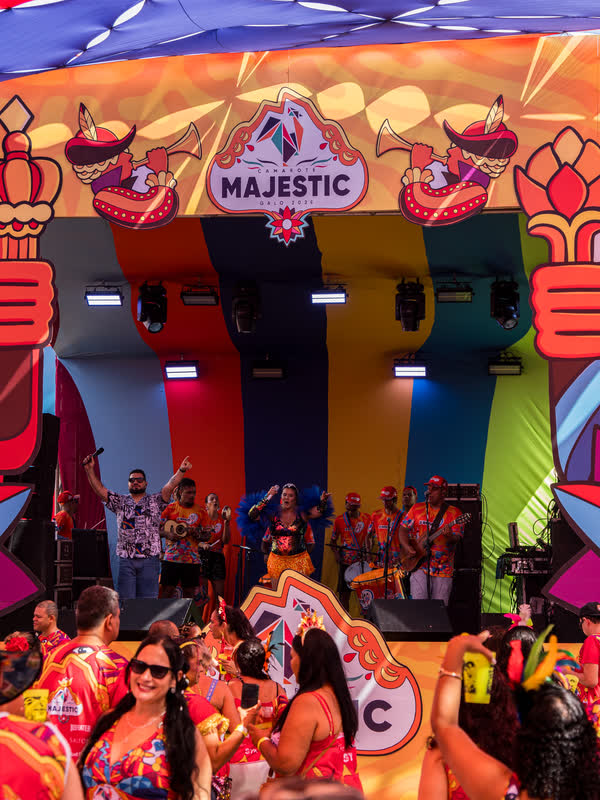 Entrada cenográfica do Camarote Majestic, com o brasão da marca sobre um mural colorido de frevo.
