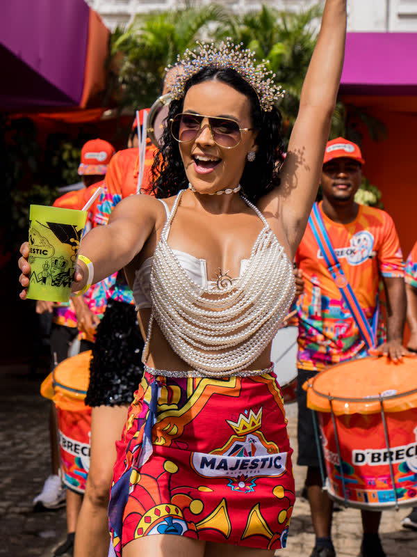 Foliã dança com os braços erguidos ao lado dos percussionistas do camarote.