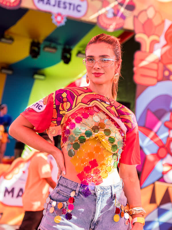 Foliã com look de carnaval posa em frente à cenografia colorida do Majestic.