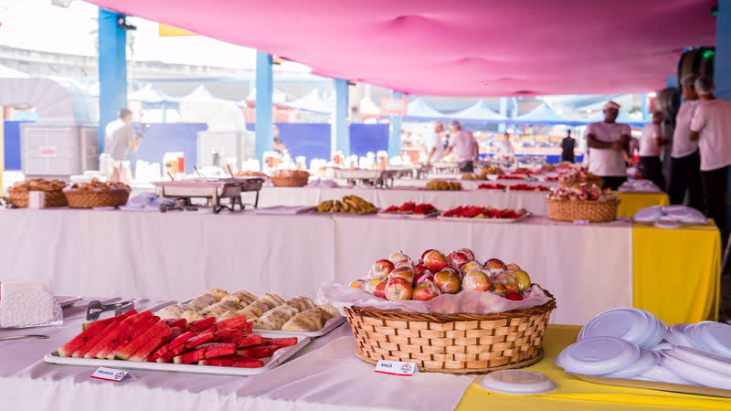 Mesa de café da manhã do Camarote Majestic com pães, bolos, frutas e sucos.